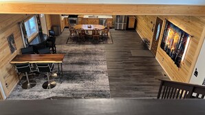 Et rummeligt køkken med moderne hårde hvidevarer, et spiseområde med et rundt bord, og et stort vindue der giver naturligt lys.