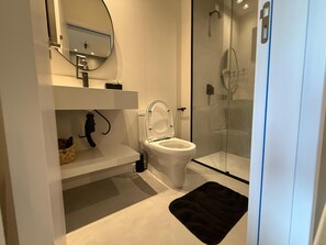 Ein modernes Badezimmer mit Toilette, Waschbecken und einer Duschkabine.