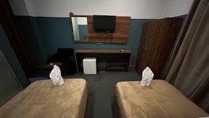 Hotellihuone, jossa on kaksi sänkyä, työpöytä, televisio ja vaatekaappi.