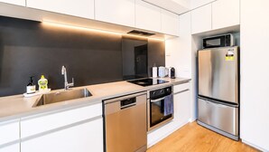 A modern kitchen with stainless steel appliances, a dishwasher, and a microwave. - Sydenham | Patio + Free Parking Near CBD (Christchurch)