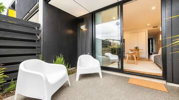 A modern exterior with a sliding glass door leading to a living area, two white chairs outside, and a small outdoor table.