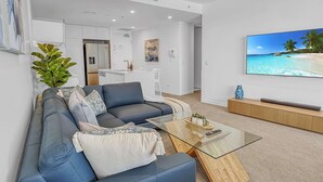 Een moderne woonkamer met een bank, salontafel en een tv waarop een strandscène te zien is.