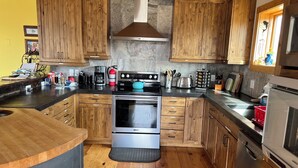 A kitchen with wooden cabinets, a stainless steel oven, a coffee maker, and a toaster. - Spacious cabin and studio in beautiful Mancos with AC and heat (Mancos)