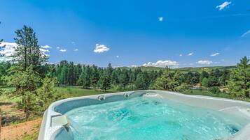 A hot tub with a clear view of a mountainous landscape and trees in the background.