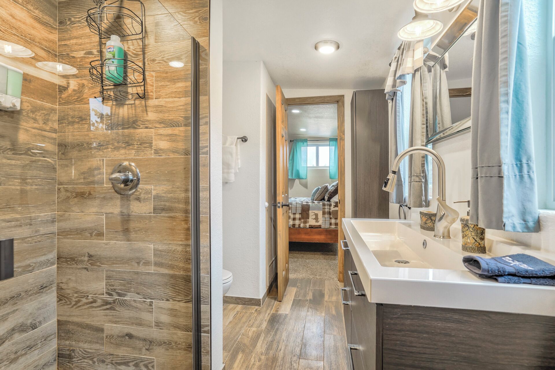 A modern bathroom with a shower, sink, and toilet.