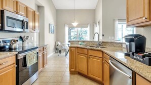 A modern kitchen with wooden cabinets, a stainless steel oven, a microwave, a coffee maker, and a granite countertop. - 333 Burford Circle Davenport (Davenport)