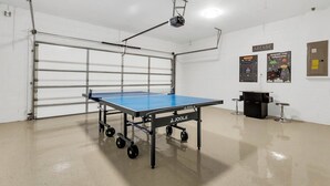 A ping pong table in a room with a white ceiling fan, a projector mounted on the ceiling, and a poster on the wall. - 333 Burford Circle Davenport (Davenport)