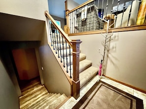 Una escalera con barandillas de madera y peldaños alfombrados en color beige.