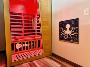 Una habitación con un armario iluminado en rojo, suelo de madera y una obra de arte de pulpo colgada en la pared.