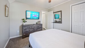 A bedroom with a bed, a dresser, a ceiling fan, a TV, and a door. - 23 Magnolia, Rydal (Rydal)