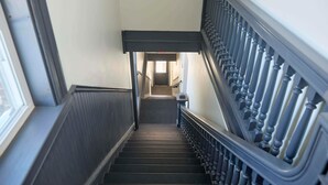 Un escalier avec des balustres sombres et une main courante, menant à l’étage supérieur.