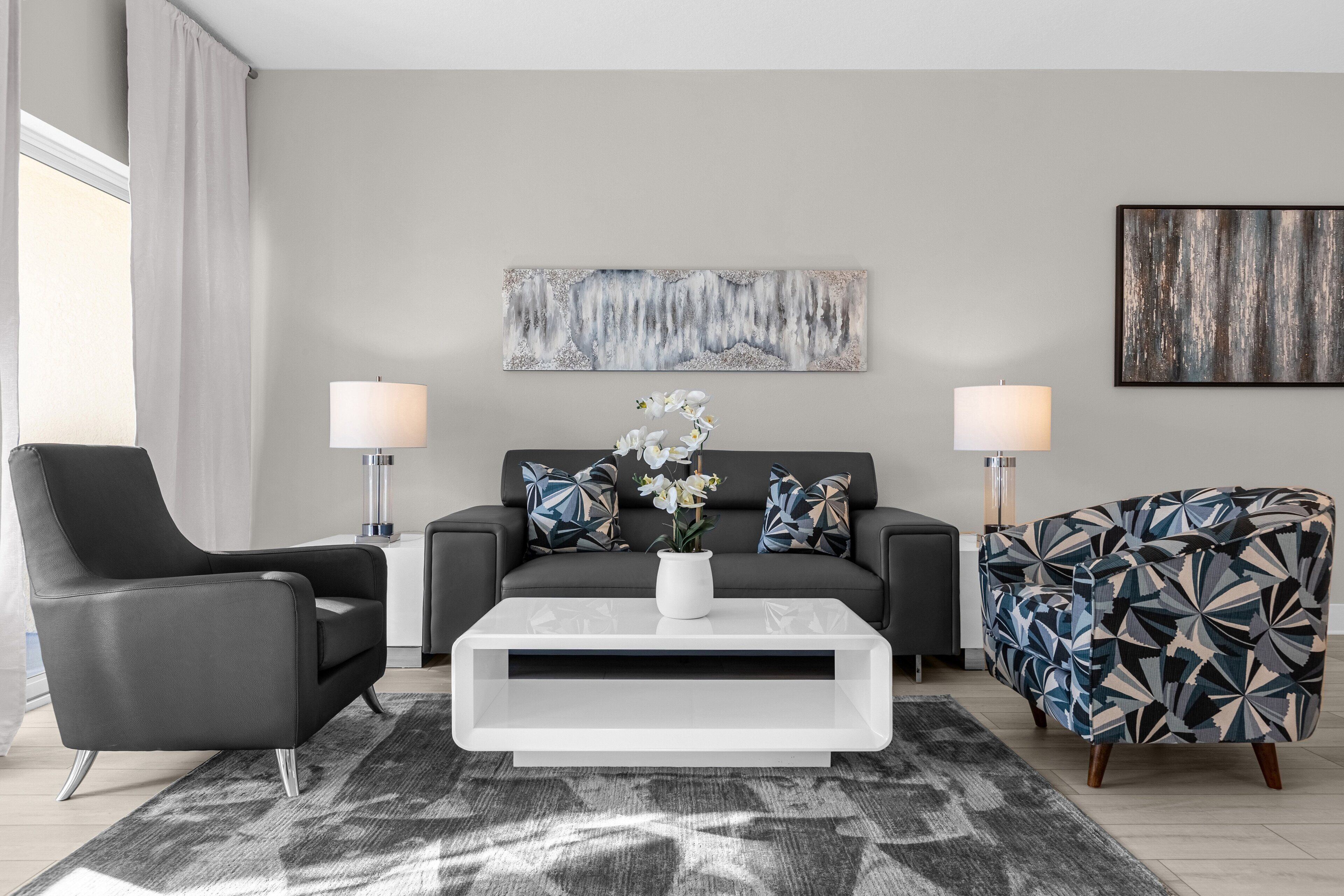 A modern living room with a sofa, two armchairs, a coffee table, and a rug.