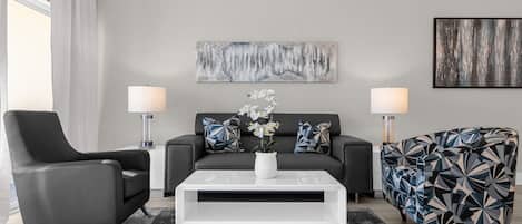 A modern living room with a sofa, two armchairs, a coffee table, and a rug.