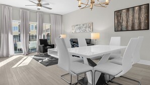A modern dining room with a white table and chairs, a ceiling fan, and a chandelier. - 6105 (Orlando)