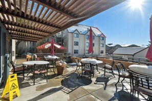 Eine Terrassesitzgruppe mit Tischen und Stühlen, ein überdachter Sitzbereich und ein Warnschild.