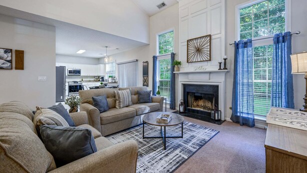 A living room with a fireplace, a sofa, a coffee table, and a view of the kitchen. - Pet-friendly 3BR w Porch & Grill Weekday Deals! (Woodstock)