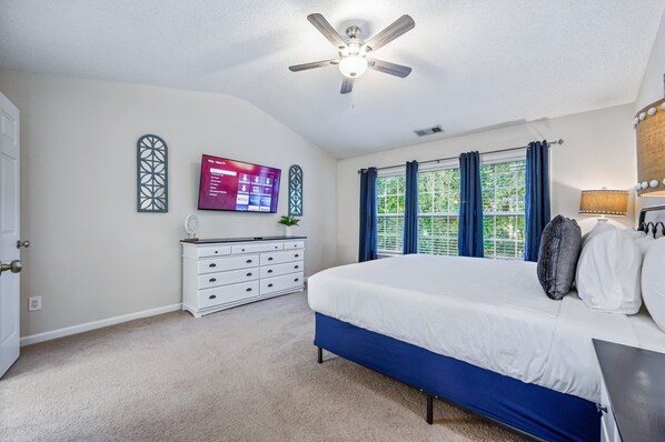 A bedroom with a bed, a ceiling fan, a dresser, a TV, and a window with curtains. - Pet-friendly 3BR w Porch & Grill Weekday Deals! (Woodstock)