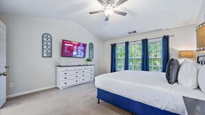 A bedroom with a bed, a ceiling fan, a TV, a dresser, and a window with curtains. - Pet-friendly 3BR w Porch & Grill Weekday Deals! (Woodstock)