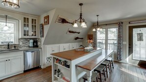 Una cocina con armarios blancos, una isla de madera e iluminación colgante.
