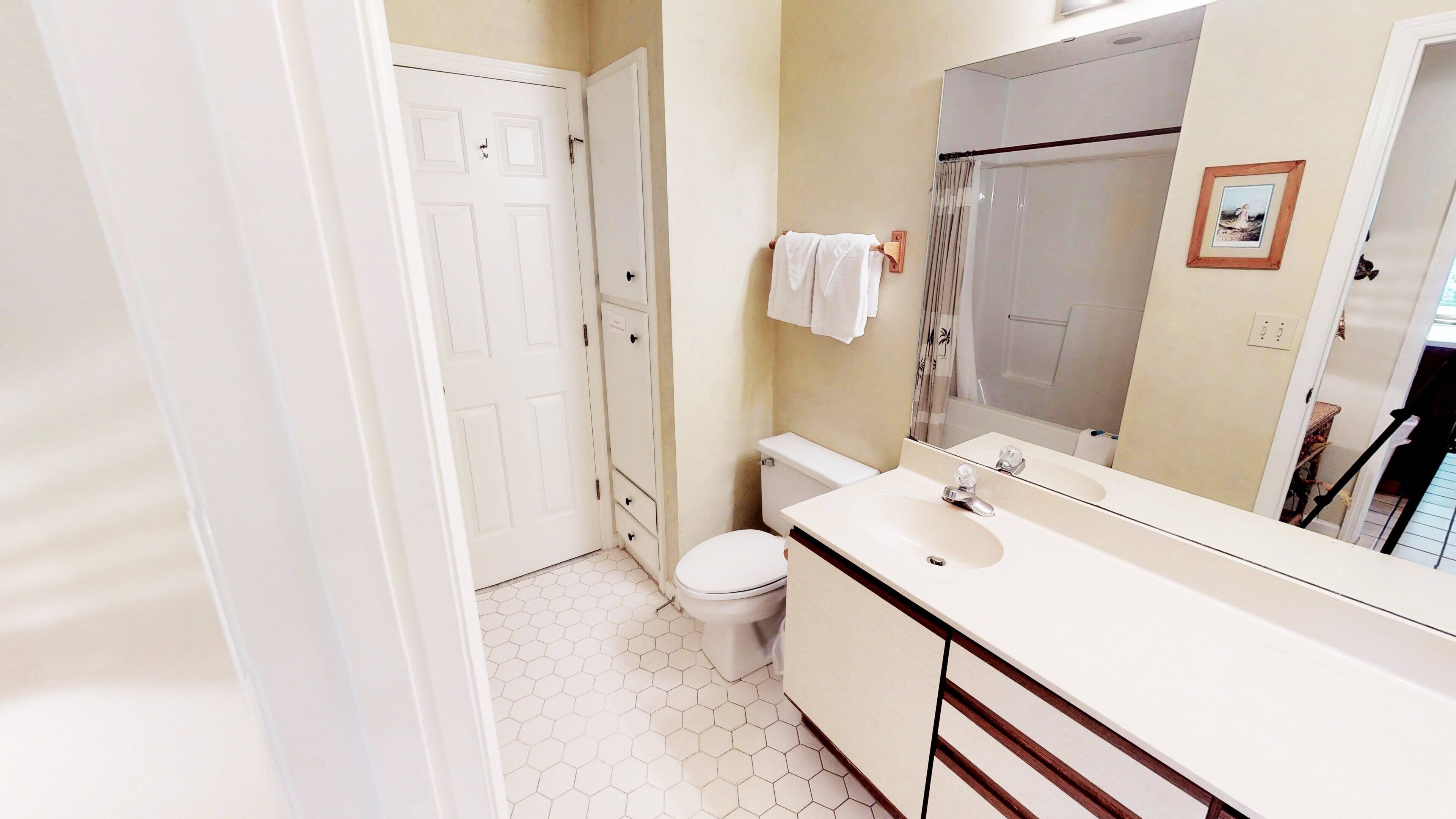 A bathroom with a white toilet, a sink with a mirror, and a shower area.