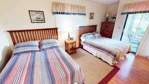 A bedroom with two beds, a nightstand, a dresser, and a window with curtains. - River Creek 1 Unit 401 (Sunset Beach)