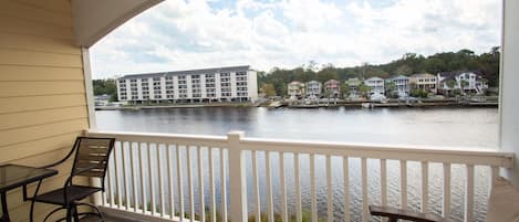 A balcony with a view of a waterfront, including a hotel and residential buildings.