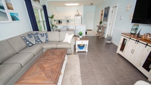 A living room with a sectional sofa, a wooden coffee table, and a kitchen in the background. - River Walk 304 (Myrtle Beach)