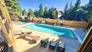 A backyard with a swimming pool, lounge chairs, and a wooden fence. - Prime Spot! Walk to Ski, Shops, and Main Street! (Park City)