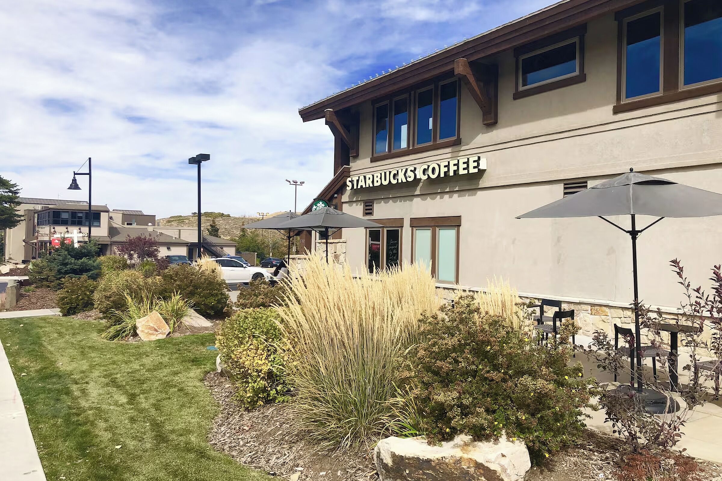 A Starbucks Coffee building with outdoor seating and landscaping.