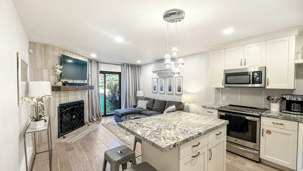 A modern kitchen with a central island, stainless steel appliances, and a dining area with bar stools. - Prime Spot! Walk to Ski, Shops, and Main Street! (Park City)