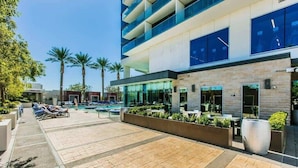 Ein modernes Hotel mit Poolbereich, Außengastronomie und Palmen.