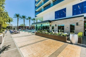 A modern hotel with a pool area, outdoor seating, and palm trees. - Palms Studio w/ Strip View & Balcony Access 36316 (Las Vegas)