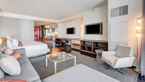 Ein modernes Hotelzimmer mit Bett, Sofa, Fernseher und Sitzecke.