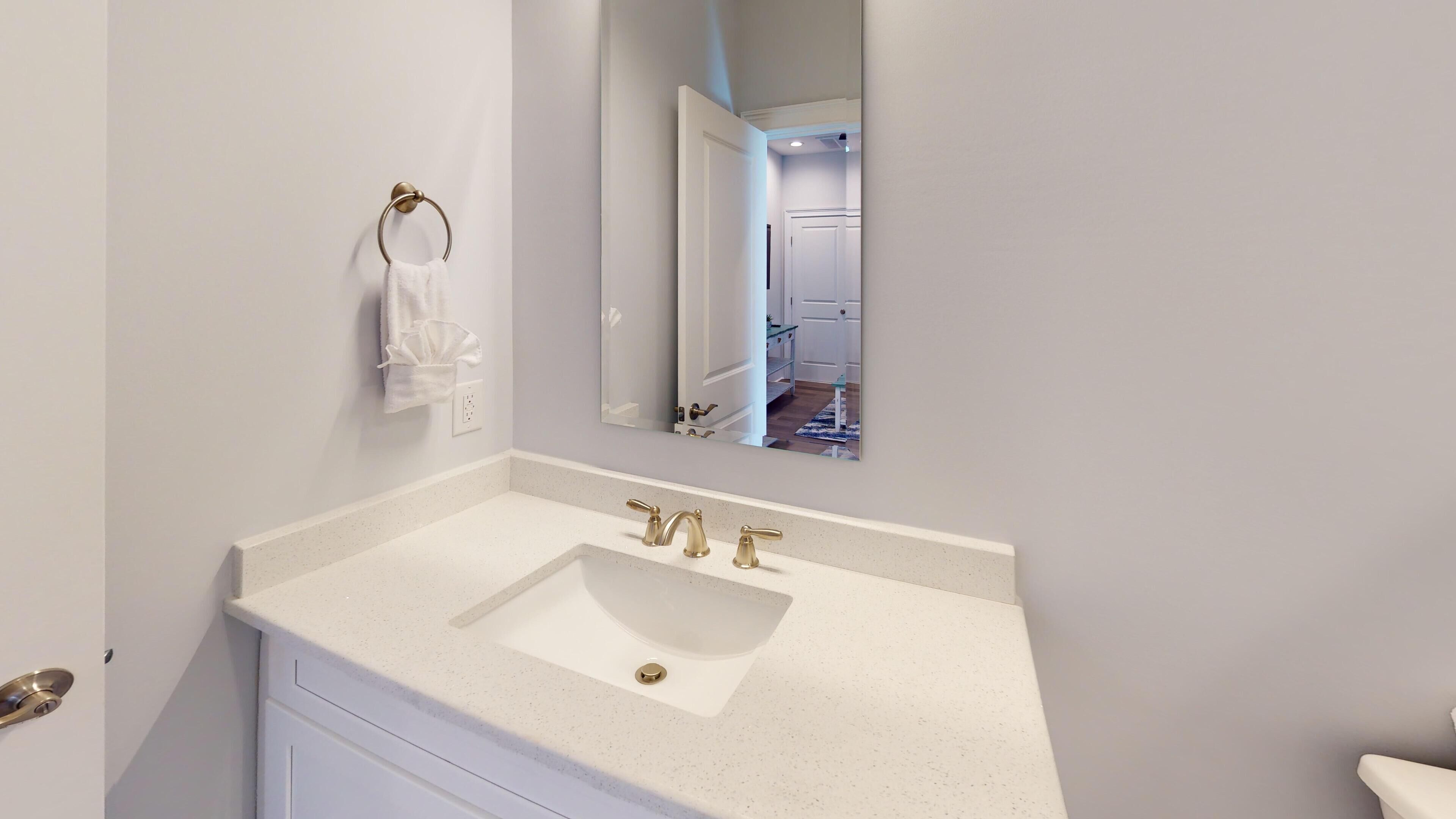 A bathroom with a white sink, gold faucets, and a towel hanging on a towel ring.