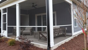 A covered porch with a ceiling fan, outdoor seating, and a view of the house.