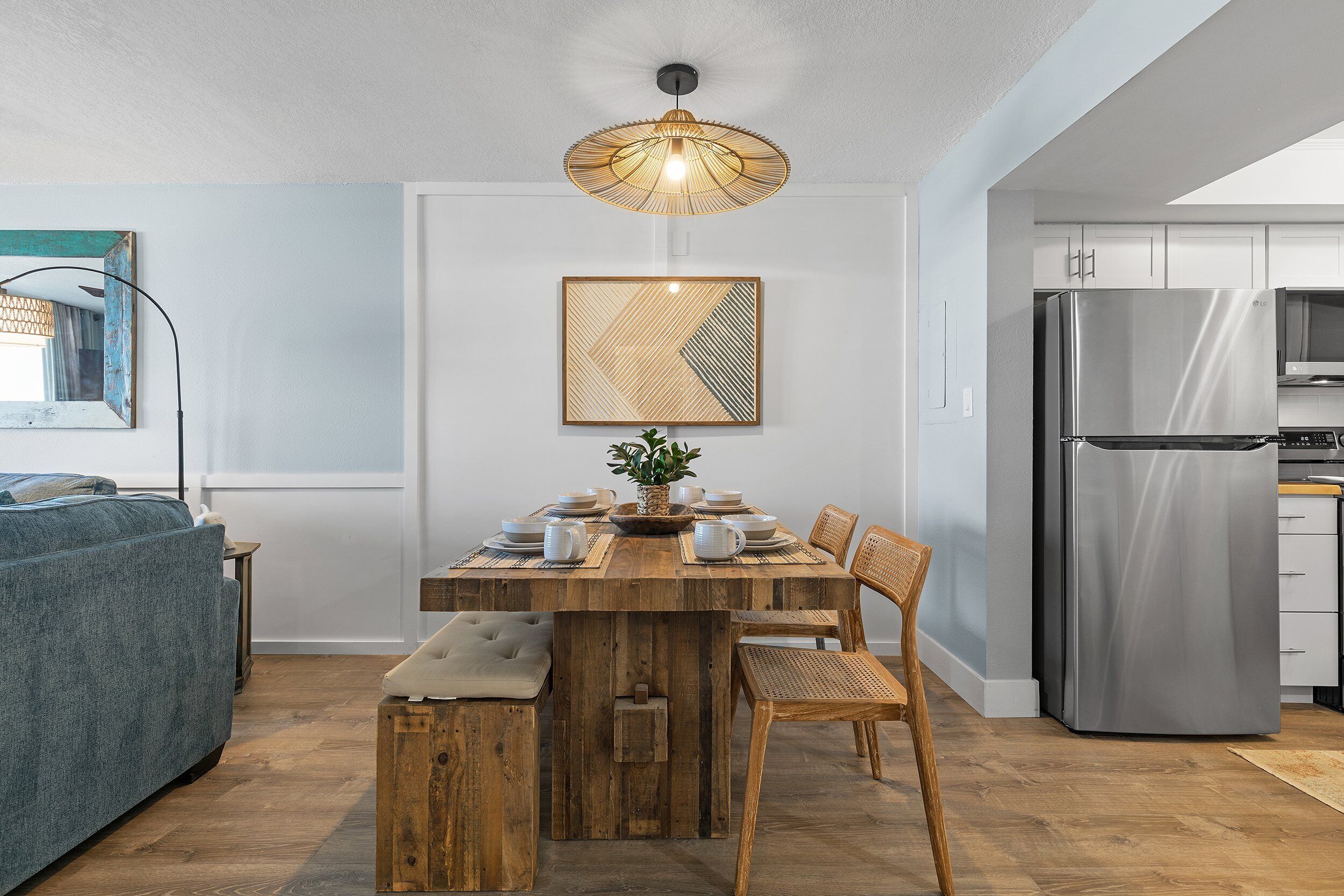 Una cocina moderna con una mesa de comedor de madera, sillas y un refrigerador de acero inoxidable.
