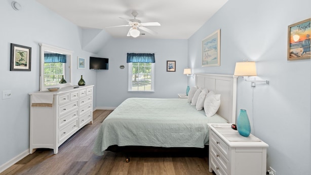A bedroom with a bed, dresser, nightstand, ceiling fan, and artwork on the walls. - Royal Poste Unit 3203 (Sunset Beach)