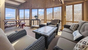 A cozy room with a wooden ceiling, large windows, a sofa, a table, and a chair. - Seacoast Sanctuary (Cape Neddick)