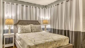 A bedroom with a large bed, two bedside tables with lamps, and a ceiling fan. - Sandhill Flat (Gary)