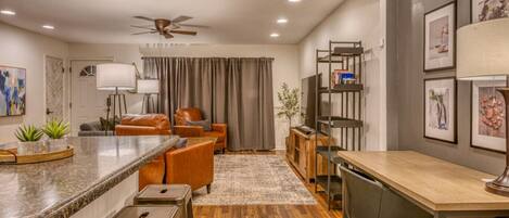 A modern kitchen with a granite countertop, bar stools, and a dining table.