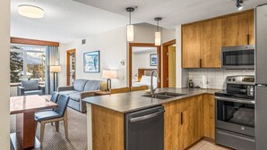 A modern kitchen with wooden cabinets, a stainless steel refrigerator, and a built-in dishwasher. - Serene 1BR Rockies Retreat w/ BBQ, Gym & Hot Tub (Canmore)