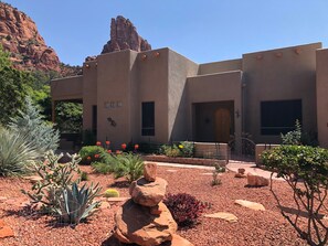 A building with a desert garden featuring cacti and red flowers, a rock formation, and a mountain in the background. - Sedona Quail Haven (Sedona)
