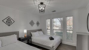 Et moderne hotelværelse med to senge, et natbord, en lampe og en loftlampe.