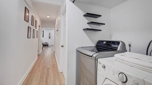 Un espace buanderie équipé d’un lave-linge, d’un sèche-linge et d’une planche à repasser.
