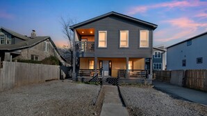 Une maison moderne à deux étages, dotée d’un balcon, d’un porche et d’une allée gravillonnée.