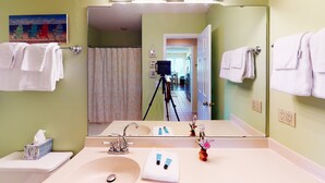 Een badkamer met een wastafel, spiegel en een camera op een statief op de achtergrond.