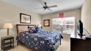 A bedroom with a bed, two bedside tables, a ceiling fan, a TV, and a window with blinds. - Cpr8972 (Kissimmee)