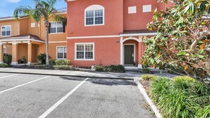 A multi-story residential building with a red facade, white trim, and a covered entrance with a porch. - Cpr8972 (Kissimmee)