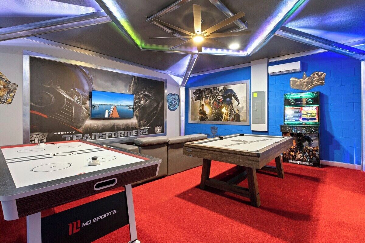 Ein Indoor-Erholungsbereich mit zwei Kicker-Tischen, einem Billardtisch und einer Spielmaschine.