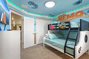Habitación infantil con literas, un escritorio y una puerta que da a otra estancia.
